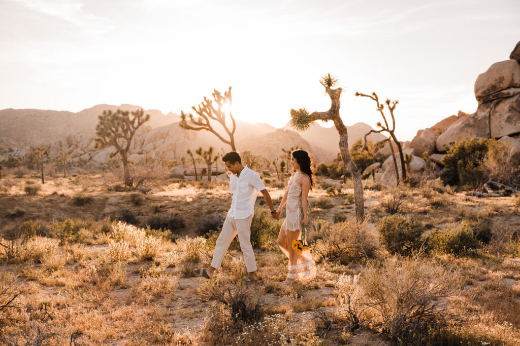 couple holding hands and walking in joshua tree national park