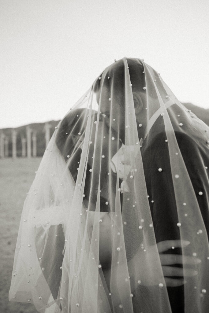 portrait of bride and groom under veil palm springs